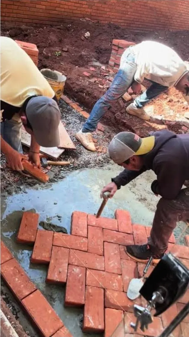 Craftspeople installing a red brick herringbone floor