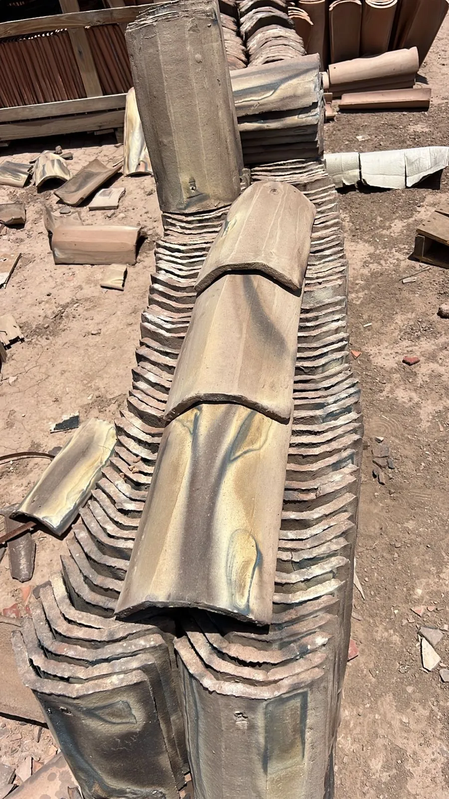 Stacked roof tiles with natural tan, charcoal, and ochre firing marks