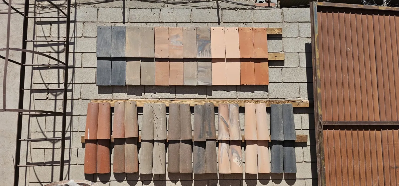 Wall display of handcrafted roof tiles in varied fired clay colors